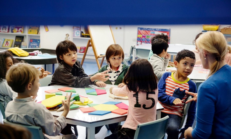Children working with colorful shapes at a classroom table